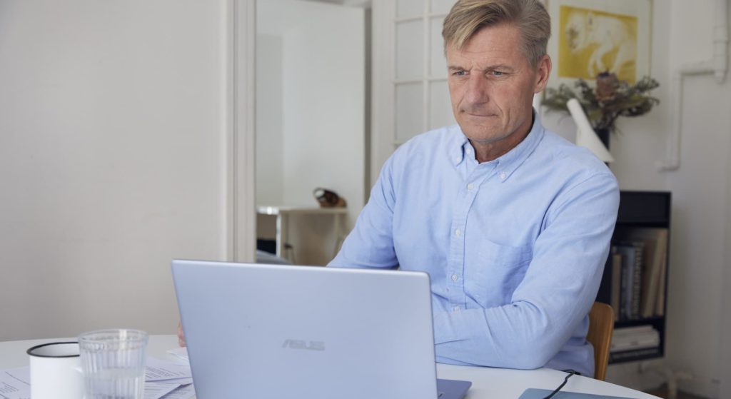 Mand sidder og kigger på sin computer