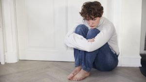 Ung pige er utilpas og sidder på gulvet